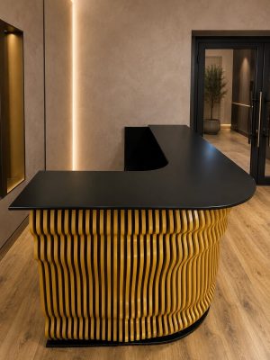 Recepție la comandă cu front 3D din riflaje aurii și blat negru curbat, vedere laterală Vila Home Design